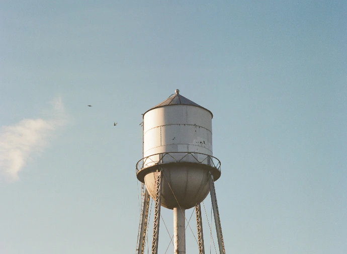 a large white water tower with a sky background